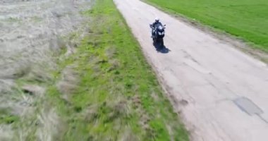 4K hava aracı görüntülerine göre motorcu eski yolda motosiklet sürüyor.