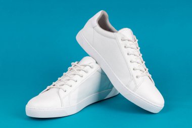 Mavi arka planda bir çift yeni beyaz spor ayakkabı