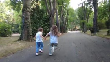 Parkta koşan iki küçük kız. Mutlu kız kardeşler, eğleniyorlar. Aile aktivitesi açık havada.