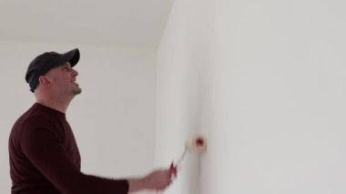  Adam bir silindirle duvarı boyuyor.