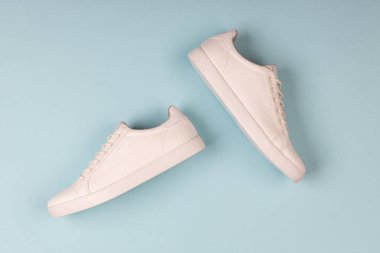 Mavi arka planda bir çift yeni beyaz spor ayakkabı