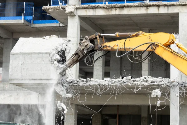 Excavator machine with hydraulic crashers at demolition of the house. House being demolished by special machinery.