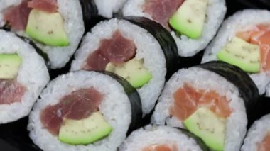 Sushi dürümlerini kapayın. Avokado, somon ve ton balıklı Japon yemeği..