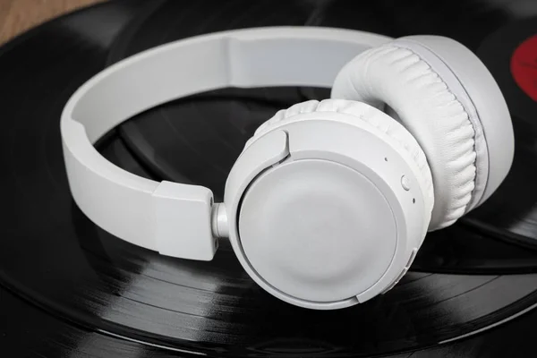 古いビニールレコード上の白いワイヤレスヘッドフォン 音楽の概念 レトロサウンドシステム — ストック写真