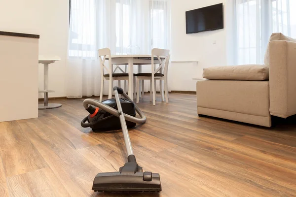 Vacuum cleaner on the wooden floor. Cleaning home