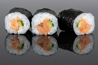 Set of three sushi rolls with salmon and avocado. Sushi with reflection. Traditional japanese food