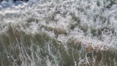 Top down view of breaking waves, whitewash. Huge swell hitting shoreline.