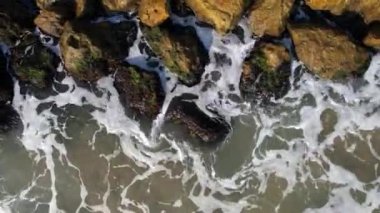 Top down view of waves crushing the coast line, rocks