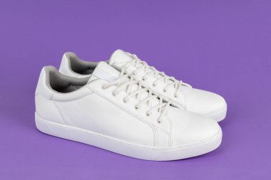 Pair of new white sneakers on purple background