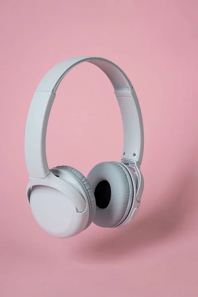 ピンクの背景にワイヤレスホワイトのヘッドフォン 音楽の概念 ピンクの背景のイヤホン — ストック写真