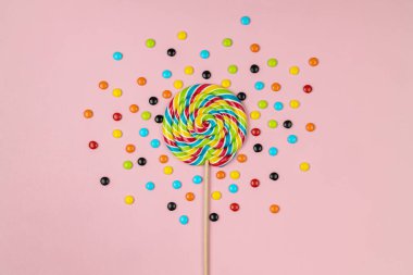 Tatlı lolipop ve pembe arka planda renkli şeker hapları. 