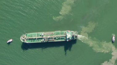 Top down view of Tug boat assisting big oil, chemical tanker. Large oil, chemical tanker ship enters the port escorted by tugboat.