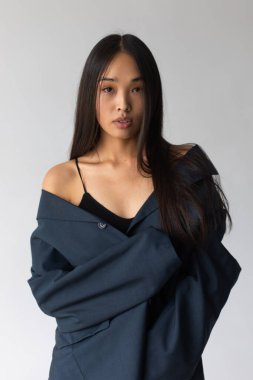 Beyaz arka planda poz veren ceketli çekici Asyalı kadın..