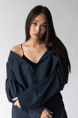 Beyaz arka planda poz veren ceketli çekici Asyalı kadın..