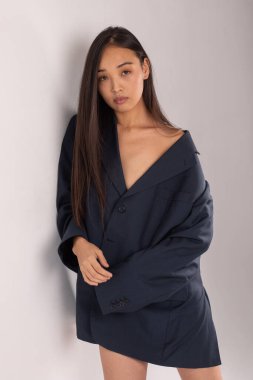 Beyaz arka planda poz veren ceketli çekici Asyalı kadın..