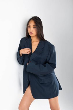 Beyaz arka planda poz veren ceketli çekici Asyalı kadın..