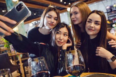 Bir grup kız arkadaş bir restoranda akşam yemeğinde selfie çekiyorlar..