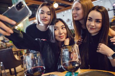Bir grup kız arkadaş bir restoranda akşam yemeğinde selfie çekiyorlar..