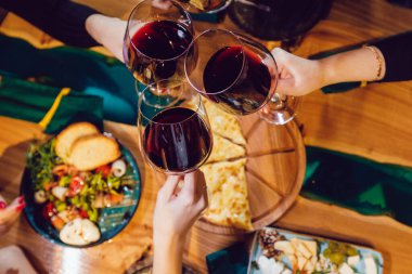 Kadehleri şarapla tokuşturan bir arkadaş grubunun üst görüntüsü.