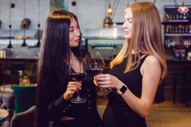 Bir restoranda elinde şarap kadehi olan iki kız arkadaş..