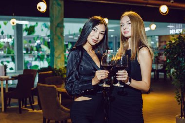Bir restoranda elinde şarap kadehi olan iki kız arkadaş..