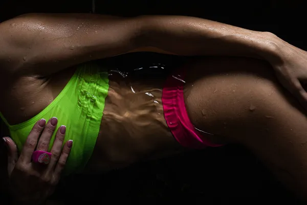 穿着鲜艳内衣裤的性感女人躺在有水的黑暗浴缸里 — 图库照片
