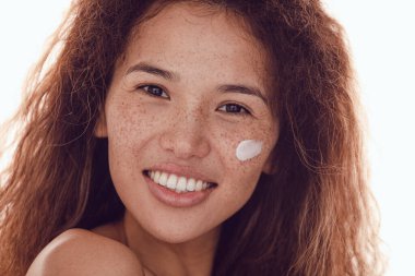 Gülümseyen kadın portresi kıvırcık saçlı ve yanağında nemlendirici olan çilli..