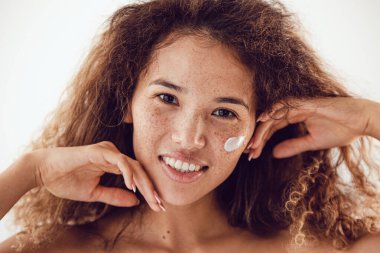 Gülümseyen kadın portresi kıvırcık saçlı ve yanağında nemlendirici olan çilli..