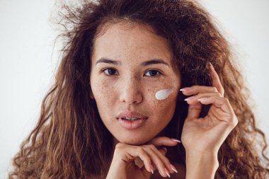Yüzünde krem olan genç ve güzel bir kadın.