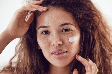 Yüzünde krem olan genç ve güzel bir kadın.