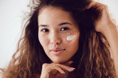 Yüzünde krem olan genç ve güzel bir kadın.