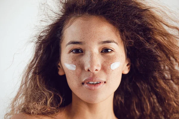 Young beautiful woman with cream on her face. — Stockfoto