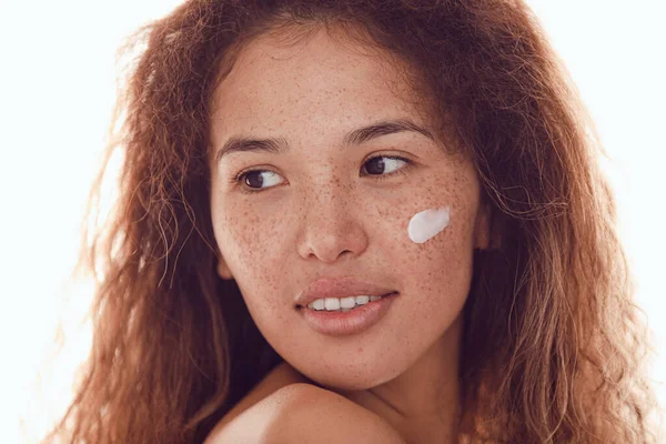 Gülümseyen kadın portresi kıvırcık saçlı ve yanağında nemlendirici olan çilli..