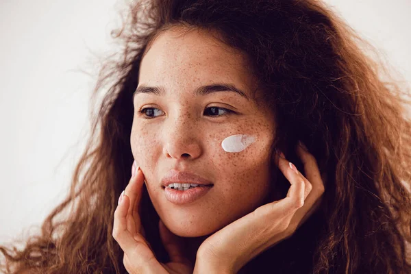 Young beautiful woman with cream on her face. — Fotografia de Stock