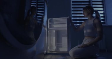 Kadın buzdolabını açıyor ve gecenin bir yarısı bir şişe şarap çıkarıyor..