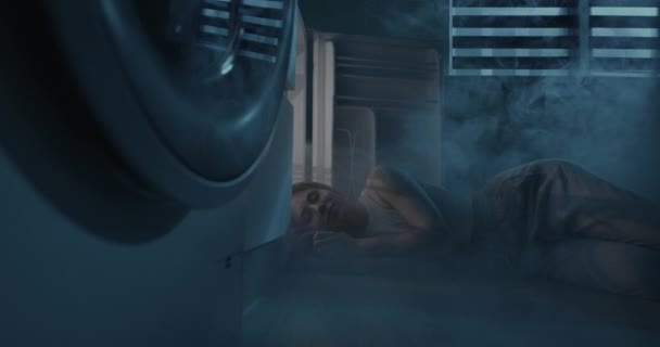 Una joven está durmiendo junto al refrigerador abierto. La chica escapa del calor sin aire acondicionado. — Vídeo de stock