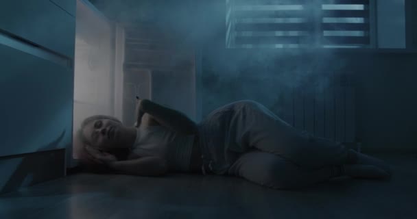 Młoda kobieta śpi przy otwartej lodówce. Dziewczyna ucieka z gorąca bez klimatyzacji. — Wideo stockowe