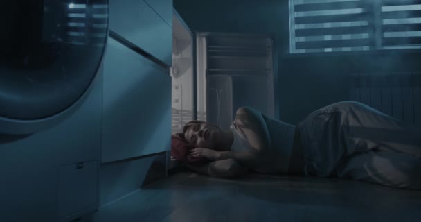 U otevřené ledničky spí mladá žena. Dívka uniká z tepla bez klimatizace. — Stock video