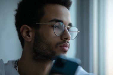 Gözlüklü, akıllı telefon kullanan Afro-Amerikan bir adamın portresi..