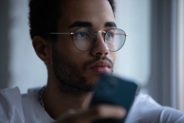 Gözlüklü, akıllı telefon kullanan Afro-Amerikan bir adamın portresi..