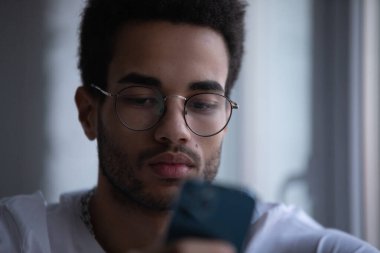 Gözlüklü, akıllı telefon kullanan Afro-Amerikan bir adamın portresi..