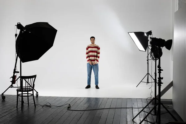 Молодий афроамериканець у смугастому светрі на білому тлі у фотостудії.. — стокове фото