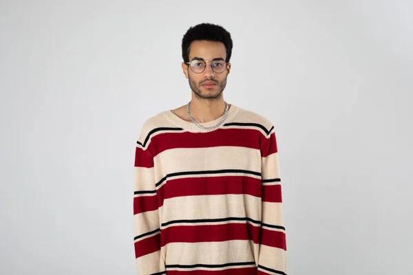 Fiatal afro-amerikai férfi szemüvegben és csíkos pulóver áll a fehér háttér. — Stock Fotó