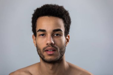 Kirli sakallı ve çıplak omuzlu Afro-Amerikan bir erkeğin portresi..