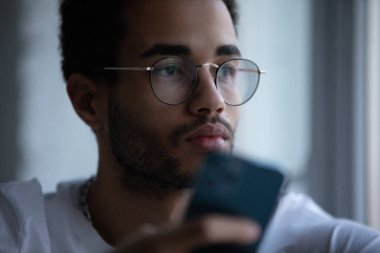 Gözlüklü, akıllı telefon kullanan Afro-Amerikan bir adamın portresi..