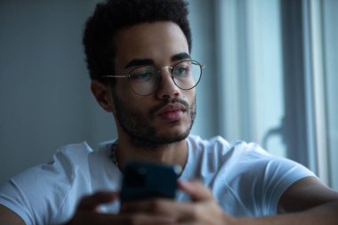 Gözlüklü, akıllı telefon kullanan Afro-Amerikan bir adamın portresi..