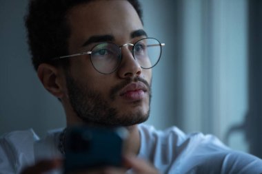 Gözlüklü, akıllı telefon kullanan Afro-Amerikan bir adamın portresi..