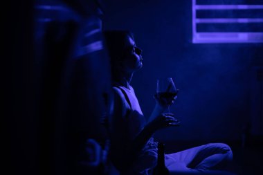 Mutsuz kadın karanlıkta buzdolabının yanında oturmuş şarap içiyor..