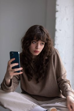 Kıvırcık saçlı çekici genç kadın selfie çekiyor..