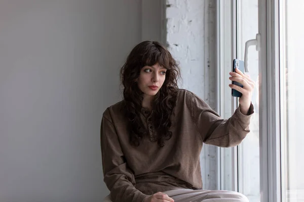 Jovem atraente com cabelo encaracolado leva selfie. — Fotografia de Stock